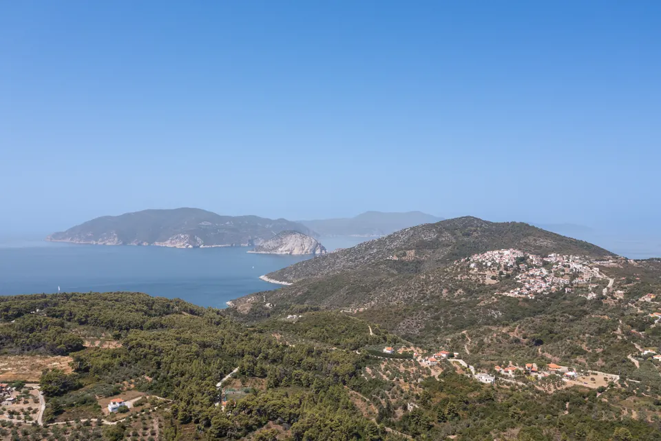 Εναέρια άποψη του Πατητηρίου στην Αλόννησο, με λόφους, οικισμό και θάλασσα.