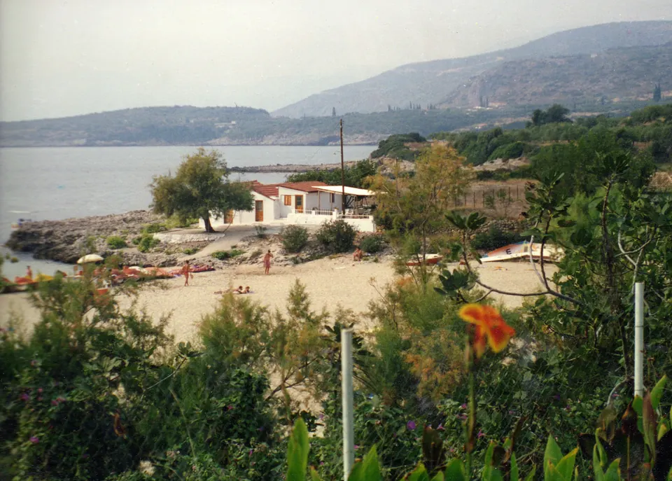 Η παραλία Καλογριά στη Στούπα της Μάνης, με βράχια, θάμνους και βουνά πίσω από τον κόλπο.